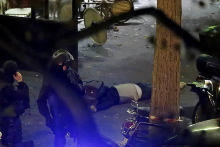 
	Policiais pr&oacute;ximos a v&iacute;tima do lado de fora da casa de shows Bataclan, em Paris, ap&oacute;s ataque
 (Christian Hartmann/Reuters)
