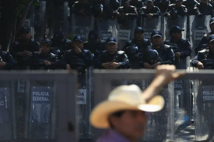 Policiais observam fazendeiros durante protesto na Cidade do México por caso de estudantes desaparecidos (Carlos Jasso/Reuters)