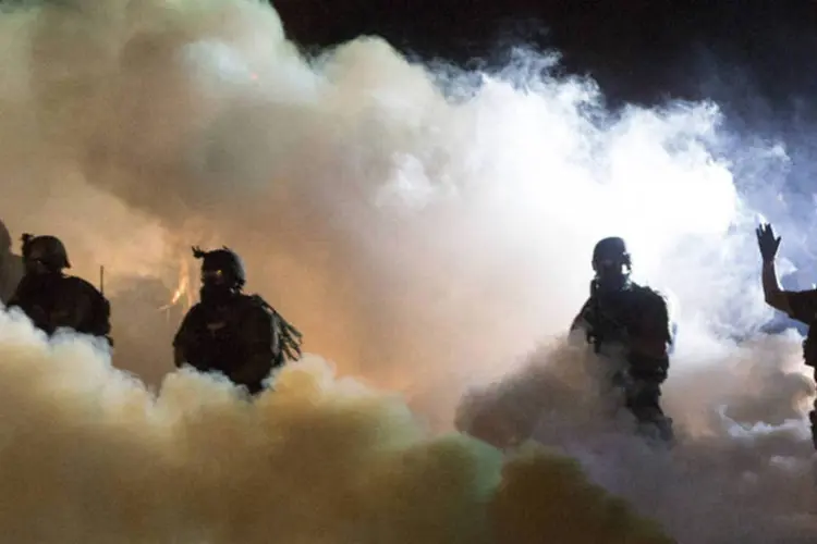 Policiais com bombas de fumaça: manifestantes têm se reunido todas as noites desde sábado, quando jovem negro foi morto a tiros (Mario Anzuoni/Reuters)
