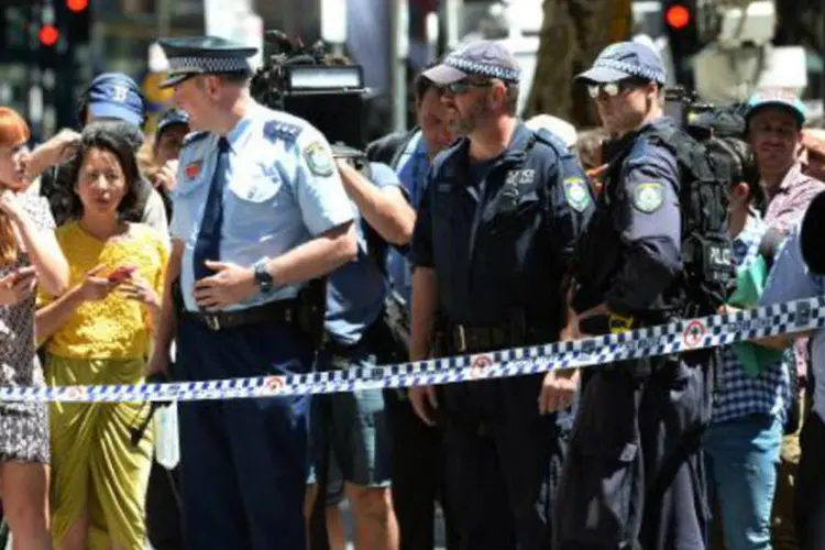 Policiais conversam com curiosos perto do café onde ocorreu o sequestro em Sydney, Austrália (Peter Parks/AFP)