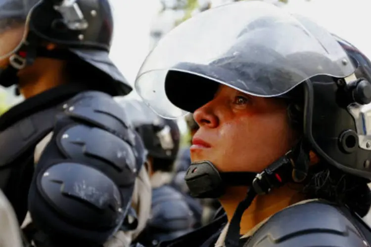 Policiais venezuelanos observam protesto: Ministério Público informou que 55 pessoas permanecem detidas, entre elas, 11 funcionários das forças de segurança (Jorge Silva/Reuters)