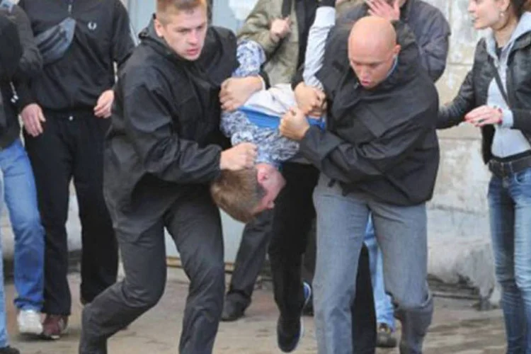 Policiais à paisana levam carregam um dos jovens detidos durante os protestos (Victor Drachev/AFP)