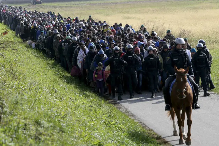 Policiais conduzem refugiados na Eslovênia (Srdjan Zivulovic/Reuters)