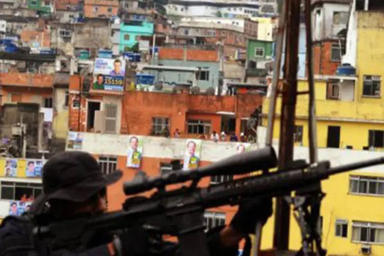 
	Policial se posiciona na favela da Rocinha, no Rio de Janeiro: a pesquisa desfez o mito de que as regi&otilde;es de ocupa&ccedil;&atilde;o irregular carioca est&atilde;o majoritariamente em encostas
 (©AFP / Antonio Scorza)