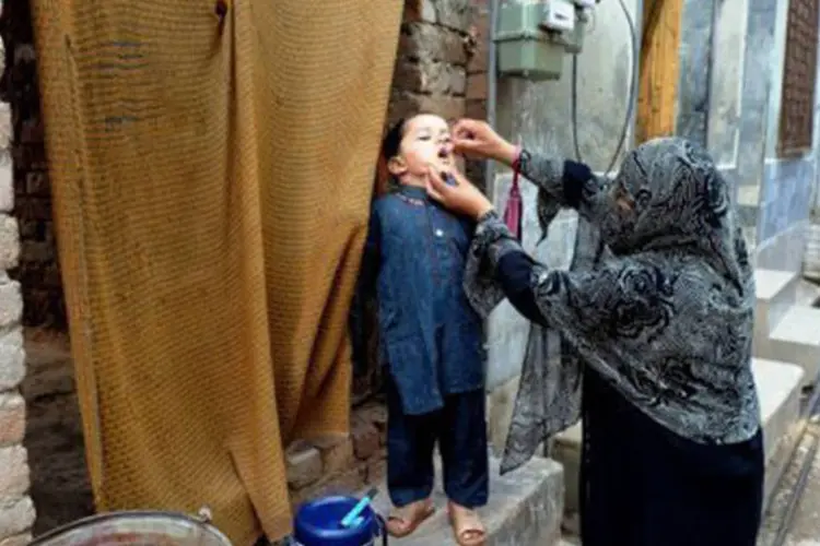 
	Funcion&aacute;ria dos servi&ccedil;os de sa&uacute;de d&aacute; vacina a crian&ccedil;a em Peshawar, no Paquist&atilde;o: a recusa de muitos pais em vacinar os filhos no pa&iacute;s &eacute; um dos obst&aacute;culos para eliminar a doen&ccedil;a
 (A. Majeed/AFP)