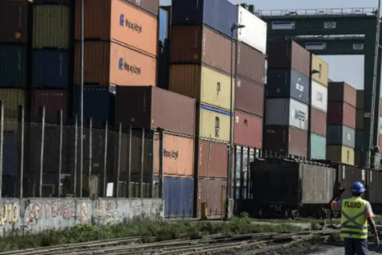 
	Trabalhador passa por containers no Porto de Santos: para 2014, o mercado tamb&eacute;m demonstrou mau humor, reduzindo a mediana esperada para o saldo de US$ 8,10 bilh&otilde;es
 (Paulo Fridman/Bloomberg)