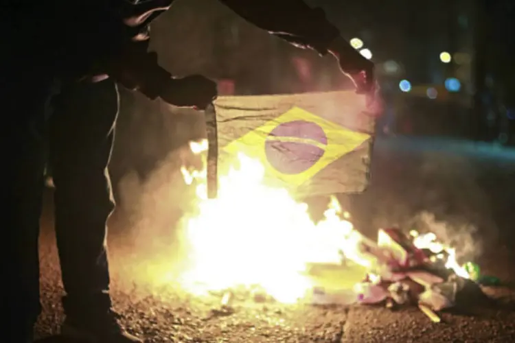 Manifestante queima a bandeira do Brasil durante protesto na Praça da Matriz, no centro de Porto Alegre: cidade também foi palco de intensas manifestações (Gustavo Vara/Reuters)