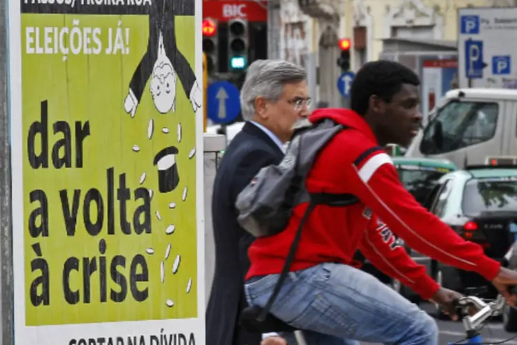 Pessoas passam em frente a cartaz com protesto contra as políticas de austeridade adotadas por Portugal (REUTERS/Jose Manuel Ribeiro)