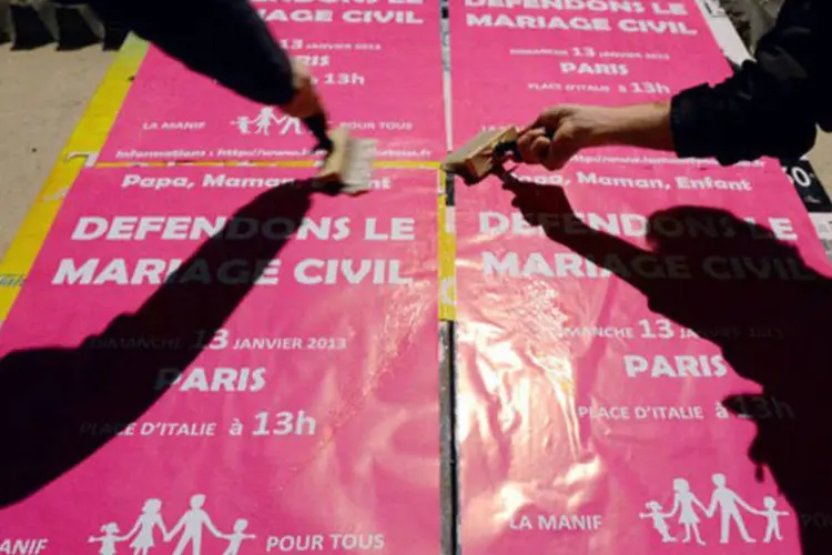 
	Militantes colam cartazes com a frase &quot;Vamos proteger o casamento civil&quot; na cidade francesa de Nantes: ainda assim, a maioria dos franceses &eacute; favor&aacute;vel ao casamento homossexual
 (Damien Meyer/AFP)