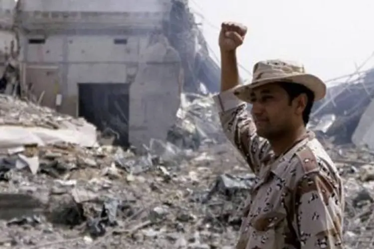 Líbio em frente a prédios destruídos em Bab Al-Aziziya, onde ficava o complexo residencial de Kadhafi (Imed Lamloum/AFP)