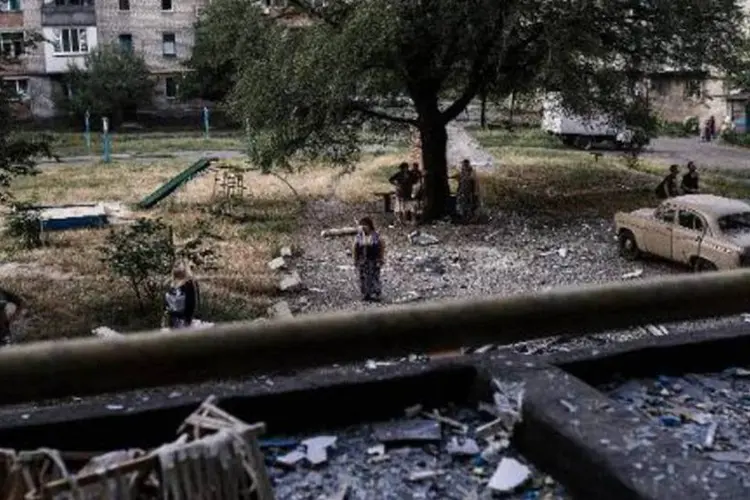 Moradores observam um prédio destruído em um bombardeio, perto de Donetsk (Dimitar Dilkoff/AFP)