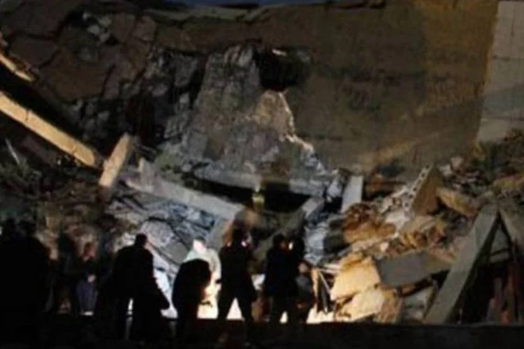 Pessoas observam destroços de um prédio administrativo da residência de Kadafi, atingido por um míssil (Imed Lamloum/AFP)