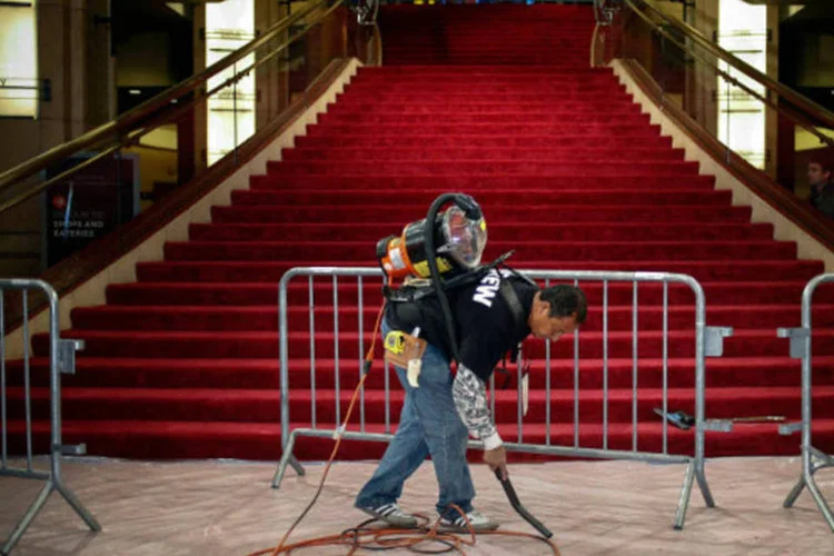 Homem usa um aspirador de pó no tapete vermelho durante os preparativos para a 86ª edição do Oscar, em Hollywood (Adrees Latif/Reuters)