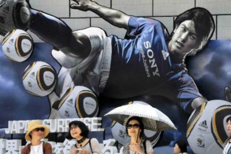 Pessoas caminham perto de propaganda de televisão da Sony em Tóquio  (Yoshikazu Tsuno/AFP)