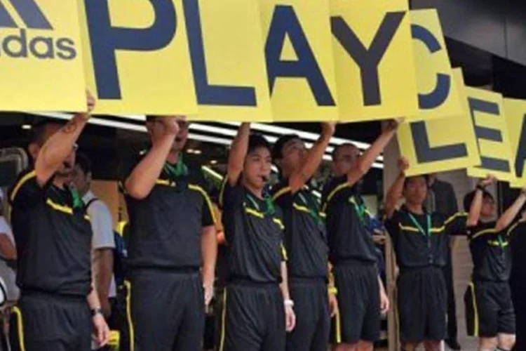 Ativistas do Greenpeace protestam em loja da Adidas com placas que formam a frase 'Jogue Limpo' (Laurent Fieve/AFP)