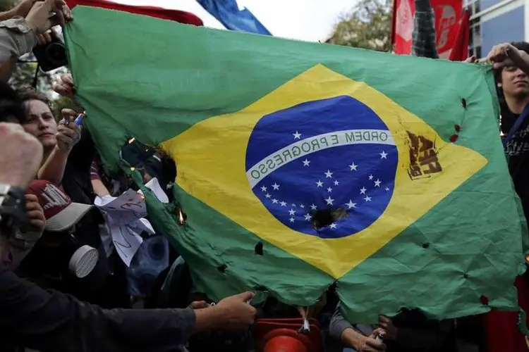 
	Manifestantes queimam bandeira do Brasil durante protestos contra a Copa
 (Sergio Moraes/Reuters)