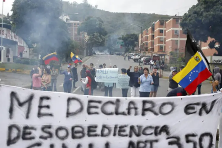 
	Manifestantes que apoiam o l&iacute;der de oposi&ccedil;&atilde;o Leopoldo L&oacute;pez erguem uma faixa para bloquear uma rua durante protesto contra o governo do presidente Nicol&aacute;s Maduro, em Caracas
 (Carlos Garcia Rawlins/Reuters)