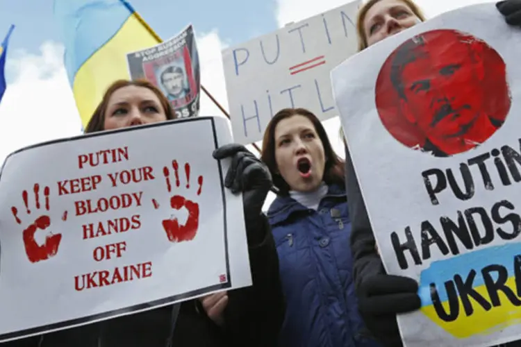 Pessoas se manifestando contra as tropas russas na Ucrânia do lado de fora de uma reunião emergencial entre ministros das Relações Exteriores da União Europeia em Bruxelas (Yves Herman/Reuters)