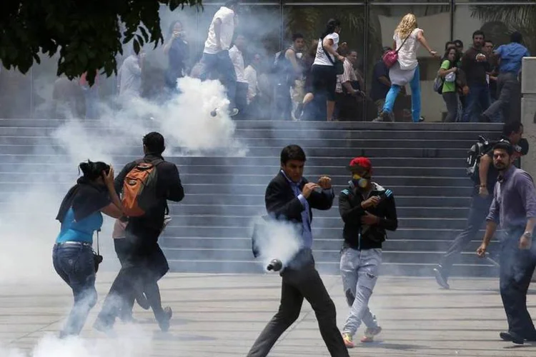 Pessoas fogem de gás lacrimogêneo durante protesto contra o presidente Nicolás Maduro, em Caracas (Carlos Garcia Rawlins/Reuters)