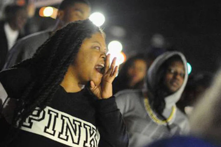 
	Manifestantes protestam em frente ao Departamento de Pol&iacute;cia de Ferguson: a cidade tem sido palco de protesto desde que o jovem negro Michael Brown foi morto por um policial branco
 (Michael B. Thomas/AFP)
