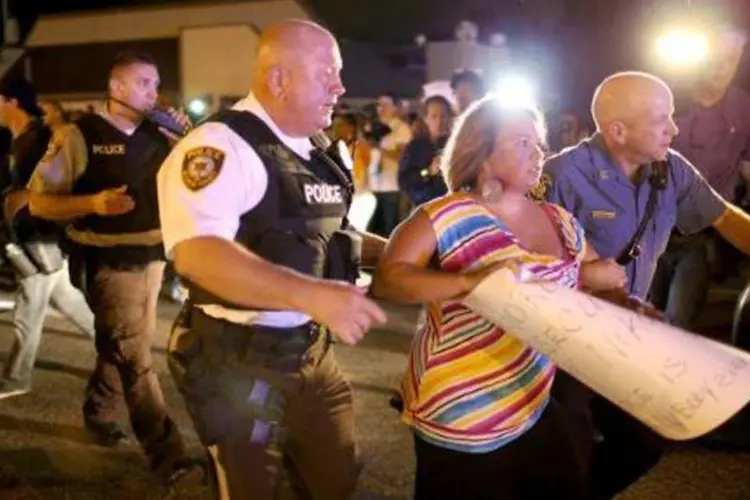 
	Um policial acompanha uma manifestante que participava de um protesto contra a morte do jovem negro Michael Brown por um policial, em Ferguson
 (Joe Raedle/AFP)