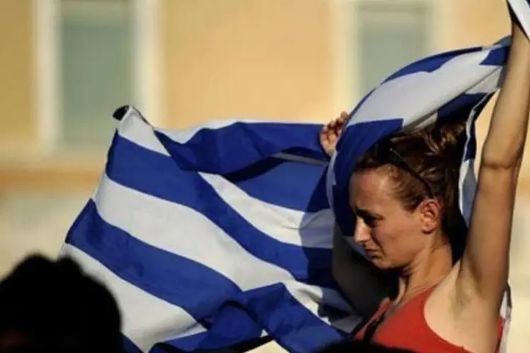 Jovem leva a bandeira grega durante um protesto contra o desemprego, que atinge mais de 50% dos jovens (Filippo Monteforte/AFP)