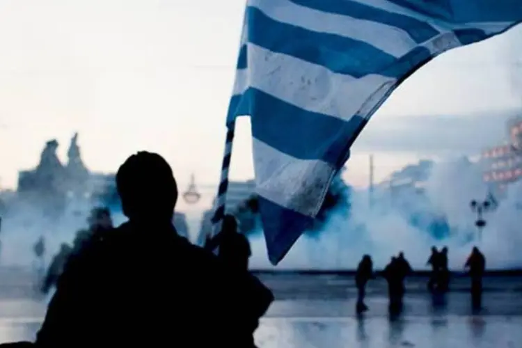 
	Homem carrega a bandeira grega em protesto na Gr&eacute;cia
 (Stefania Mizara/Corbis/Latin Stock)