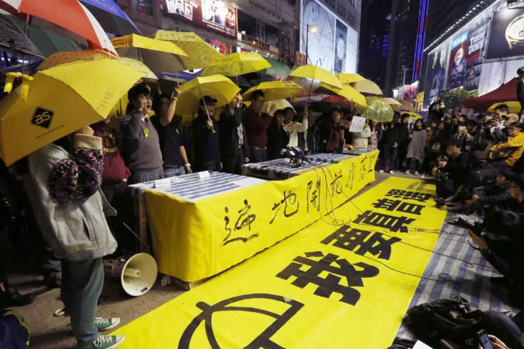 
	Manifestantes pr&oacute;-democracia carregam guarda-chuvas: a edi&ccedil;&atilde;o digital do jornal &quot;South China Morning Post&quot;, publicou que os tr&ecirc;s l&iacute;deres estudantis, Joshua Wong, Nathan Law e Alex Chow, foram acusados pelos incidentes de 26 de setembro de 2014
 (Bobby Yip/Reuters)