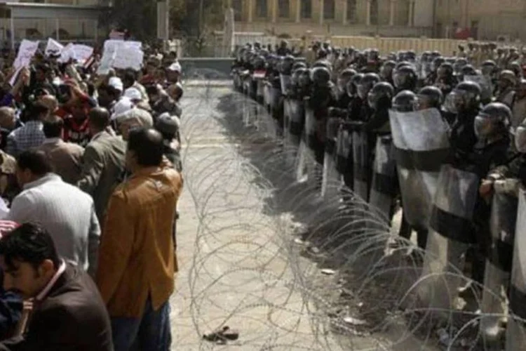 Iraquianos protestam diante de policiais em Bagdá (Ali al-Saadi/AFP)