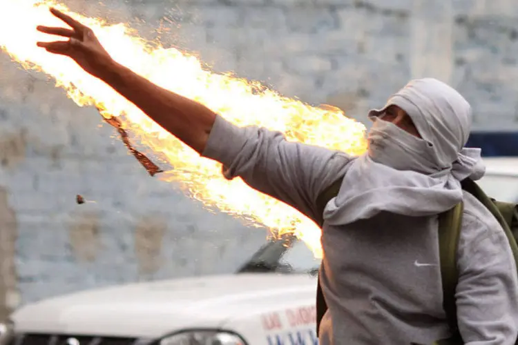 Manifestante lança um coquetel molotov contra policiais durante um protesto contra o massacre de 43 alunos de uma faculdade de professores (Carlos Jasso/Reuters)