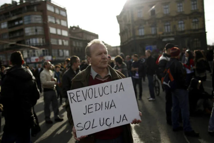 Manifestante durante um protesto contra o governo nas ruas de Sarajevo, na Bósnia. Na placa pode-se ler "a revolução é a única solução" (Dado Ruvic/Reuters)