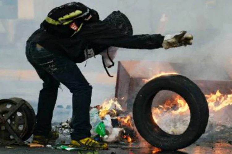 Manifestante queima pneu durante um protesto contra o governo em Caracas: Nicolás Maduro classifica protestos como "tentativa de golpe de Estado" (AFP/Arquivos)