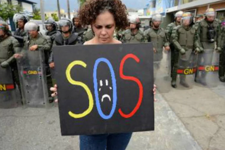 Mulher protesta na embaixada de Cuba: cerca de 30 universitários foram até a embaixada para protestar contra suposta "ingerência" da ilha no governo de Nicolás Maduro (AFP)