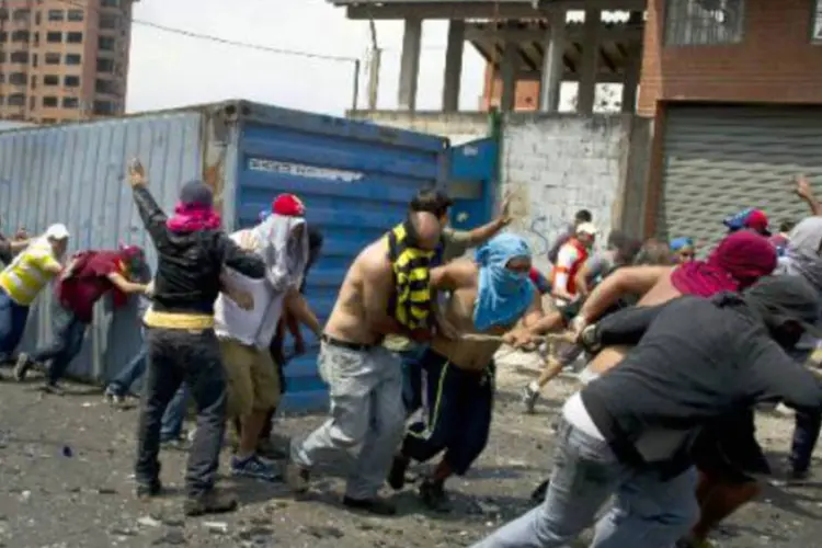 Manifestantes empurram contêiner para bloquear avenida em protesto: manifestações começaram em San Cristóbal no início de fevereiro e se espalharam por outras cidades (AFP)