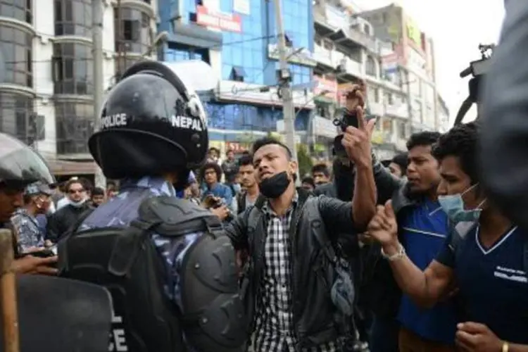 Policiais tentam conter moradores de Katmandu que protestam contra a falta de ônibus na capital do Nepal (Prakash Mathema/AFP)