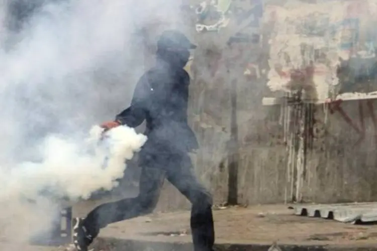 Manifestante atira lata de gás lacrimogêneo que foi jogada pela polícia, perto da Praça Tahrir, no Cairo. Protestos exigem o fim do governo militar no Egito  (Reuters)