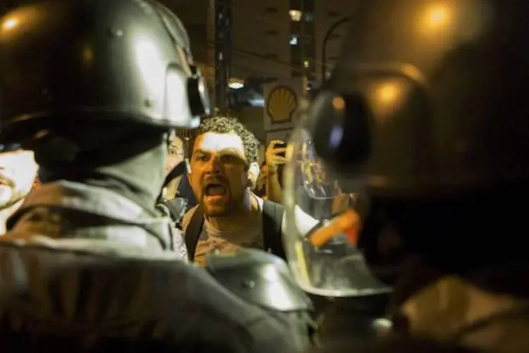 Ativista discute com policiais em protesto perto do Maracanã durante o primeiro jogo da Copa do Mundo 2014 (REUTERS/Marco Bello)