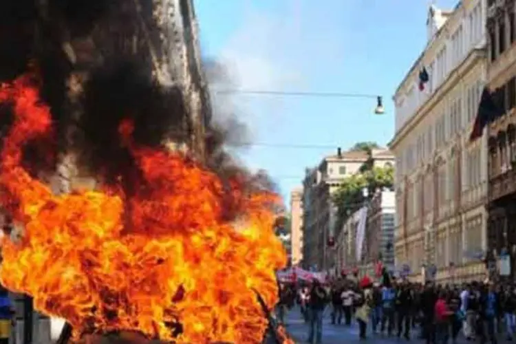 Manifestantes protestam perto de carro em chamas no centro de Roma (Alberto Pizzoli/AFP)