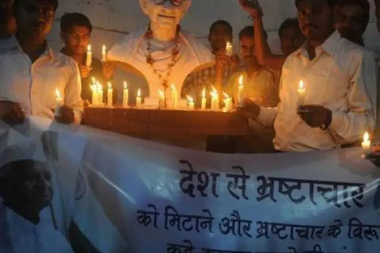Simpatizantes do ativista Anna Hazare manifestam apoio à campanha anticorrupção diante de estátua de Mahatma Ghandi (Diptendu Dutta/AFP)