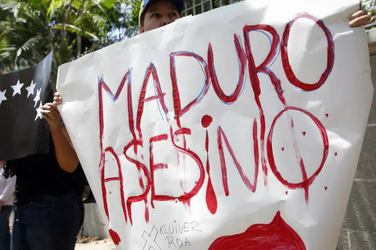 Manifestante segura cartaz onde se lê "Maduro assassino" durante protesto por morte de jovem de 14 anos na Venezuela (Carlos Garcia Rawlins/Reuters)