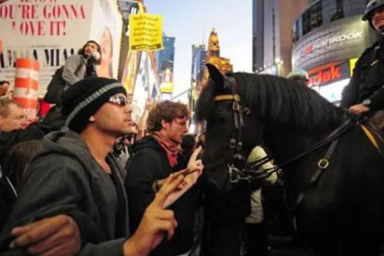 Manifestantes fazem sinais de "Paz e amor" diante da guarda montada, na Times Square (Emmanuel Dunand/AFP)