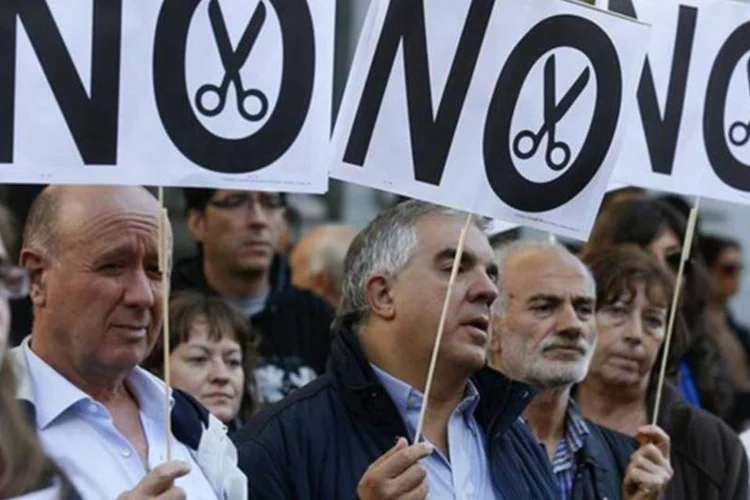 Perante uma forte presença policial, os manifestantes levam cartazes com a palavra "Não" e com desenhos de tesouras com os quais aludem aos cortes realizados pelo governo (REUTERS/Andrea Comas)