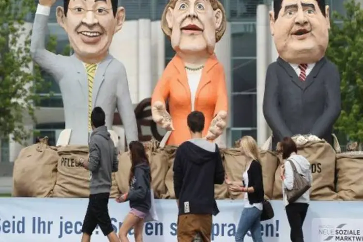 Protesto com imagens de Philipp Roesler, Angela Merkel e Sigmar Gabriel (getty images)