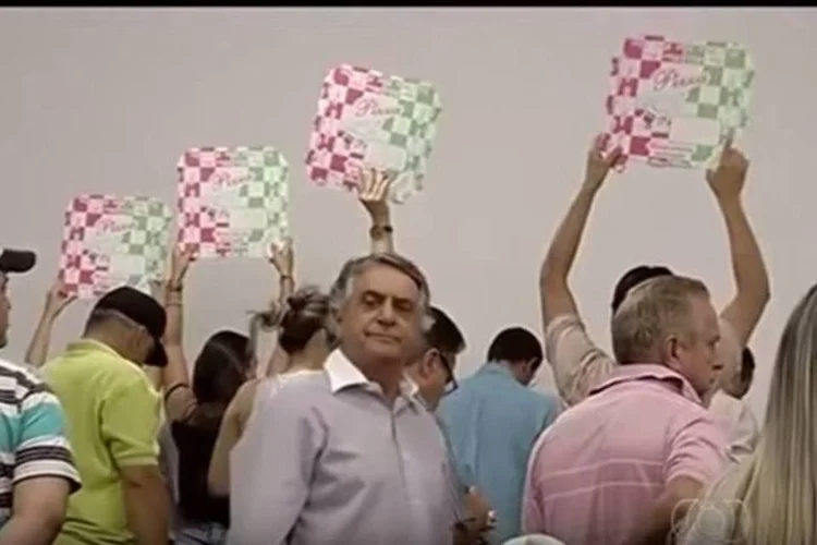 
	Pessoas carregando caixas de pizza, em protesto, na c&acirc;mara municipal de Morrinhos
 (Reprodução/YouTube)