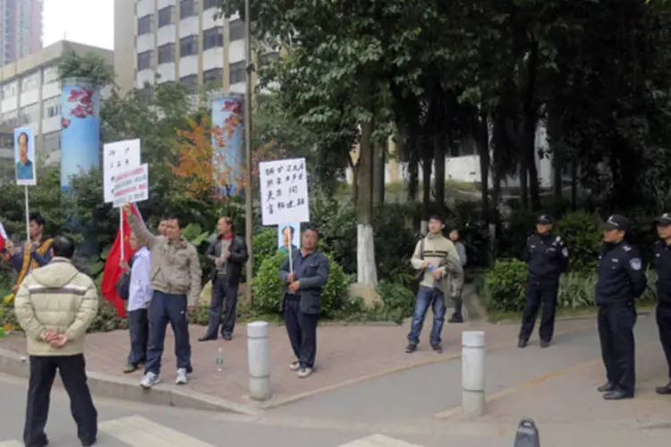 Manifestantes seguram cartazes próximos de policiais durante protesto na sede do jornal Semanário Sul (James Pomfret/Reuters)