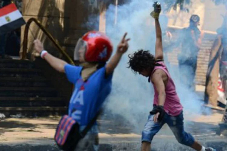 
	Manifestante eg&iacute;pcio enfrenta a pol&iacute;cia perto da embaixada americana no Cairo: os servi&ccedil;os de seguran&ccedil;a tamb&eacute;m indicaram 53 membros das for&ccedil;as de ordem feridos
 (©AFP / Khaled Desouki)