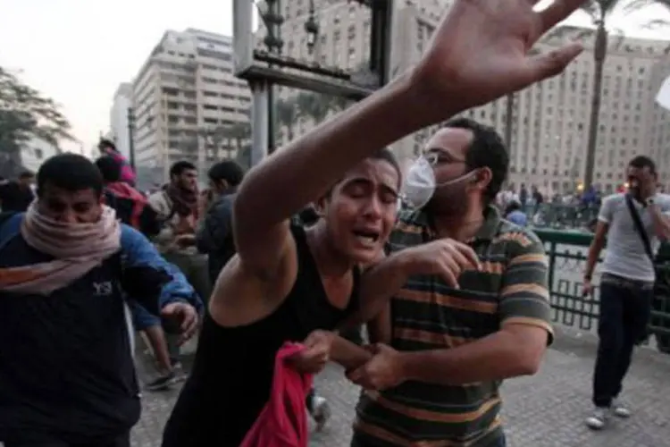 Manifestantes correm para se proteger das bombas de gás lacrimogêneo da polícia no Cairo: esses tumultos ocorrem no dia seguinte ao reforço considerável dos poderes do chefe de Estado (©AFP / Ahmed Mahmoud)