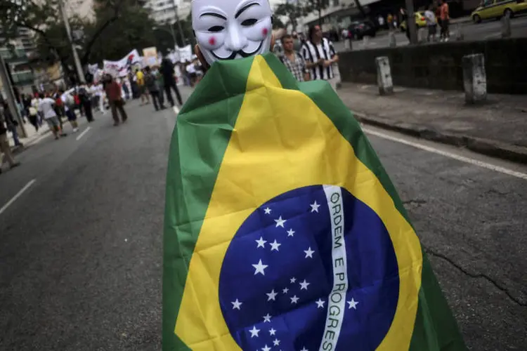 
	Manifestante usa m&aacute;scara de Guy Fawkes e se cobre com bandeira brasileira em protesto pac&iacute;fico nos arredores do Maracan&atilde;
 (REUTERS/Lunae Parracho)