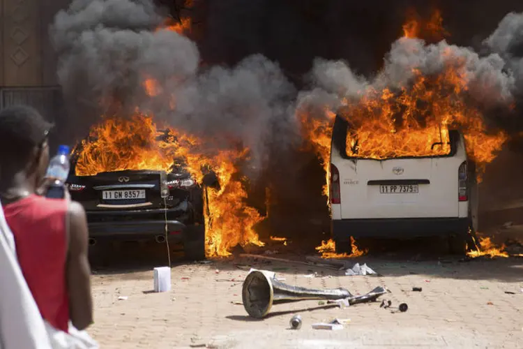 Homem observa carros em chamas em hotel da capital de Burkina Fasso, Ouagadougou (Joe Penney/Reuters)