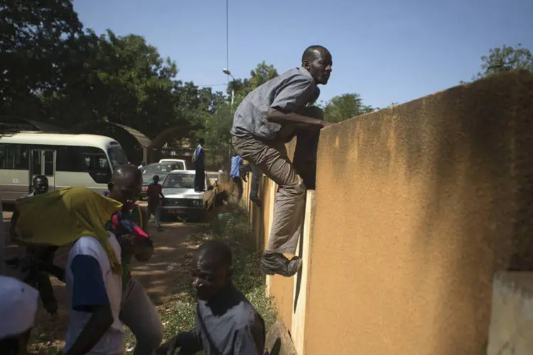 Cidadãos fogem de disparos do Exército na sede da TV estatal, na capital de Burkina Fasso, Ouagadougou, no início de novembro (Joe Penney/Reuters)